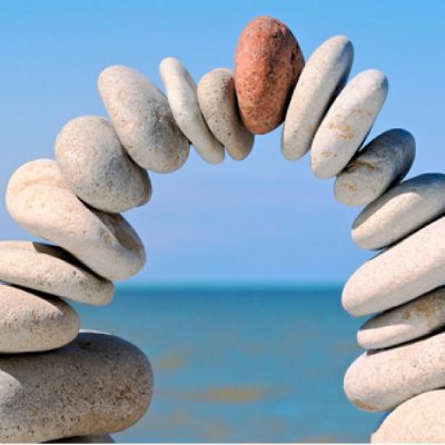 Arch of balanced stones by the sea, representing psychospirituality