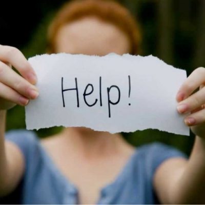 Person holding a paper sign that reads Help